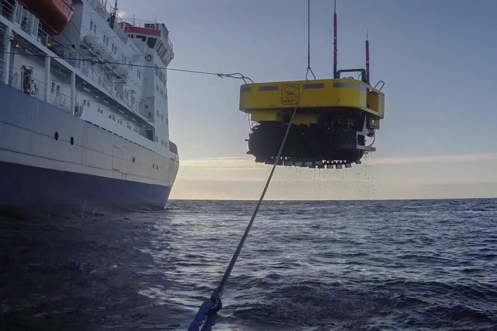 The AUV Tramper is being winched back onto the Polarstern. The device is suspended in midair.