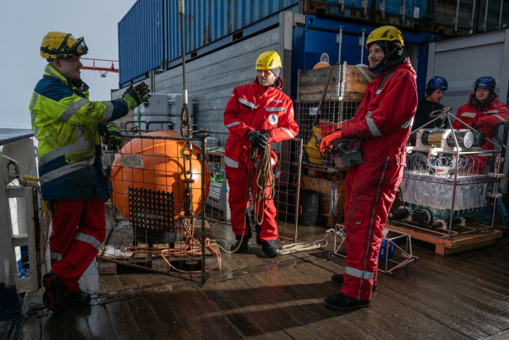 Jan Meier, the bosun, Felix Lauber, chief mate, and Philipp Klee, deck crew, during the deployment of a mooring (from left to right, photo from 31 August). The mooring hosts numerous oceanographic instruments beneath the sea ice and sits on the deep sea floor at over 4000 meters water depth.